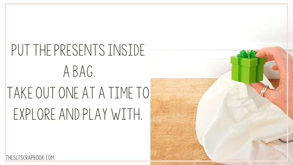 Picture of a hand taking a green present toy out of a bag. The text reads "PUT THE PRESENTS INSIDE A BAG. TAKE OUT ONE AT A TIME TO EXPLORE AND PLAY WITH"