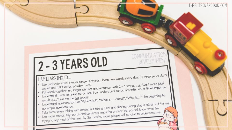 Picture of the 2-3 years old communication development handout from The SLT Scrapbook. The handout is slightly offset and there is a wooden train track on the right of the picture to show visual interest.
