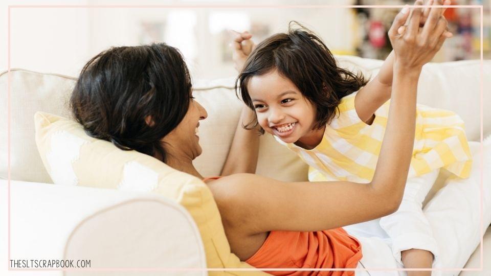 Picture of a young girl of Indian heritage playing with her mother on the sofa.